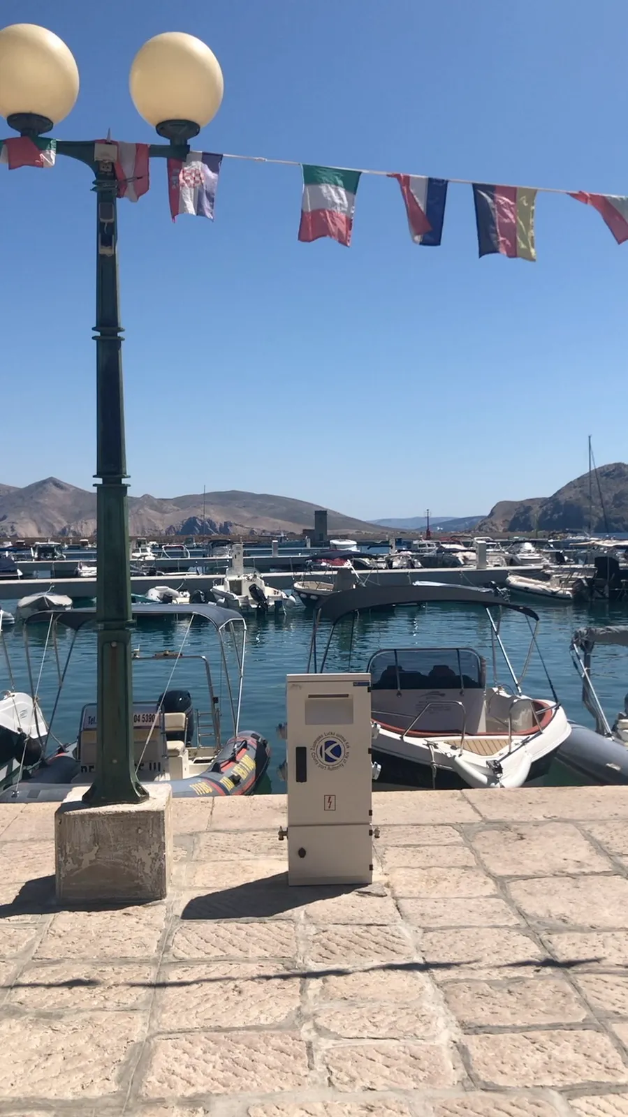 Small boats beside the stone harbour promenade in Baška
