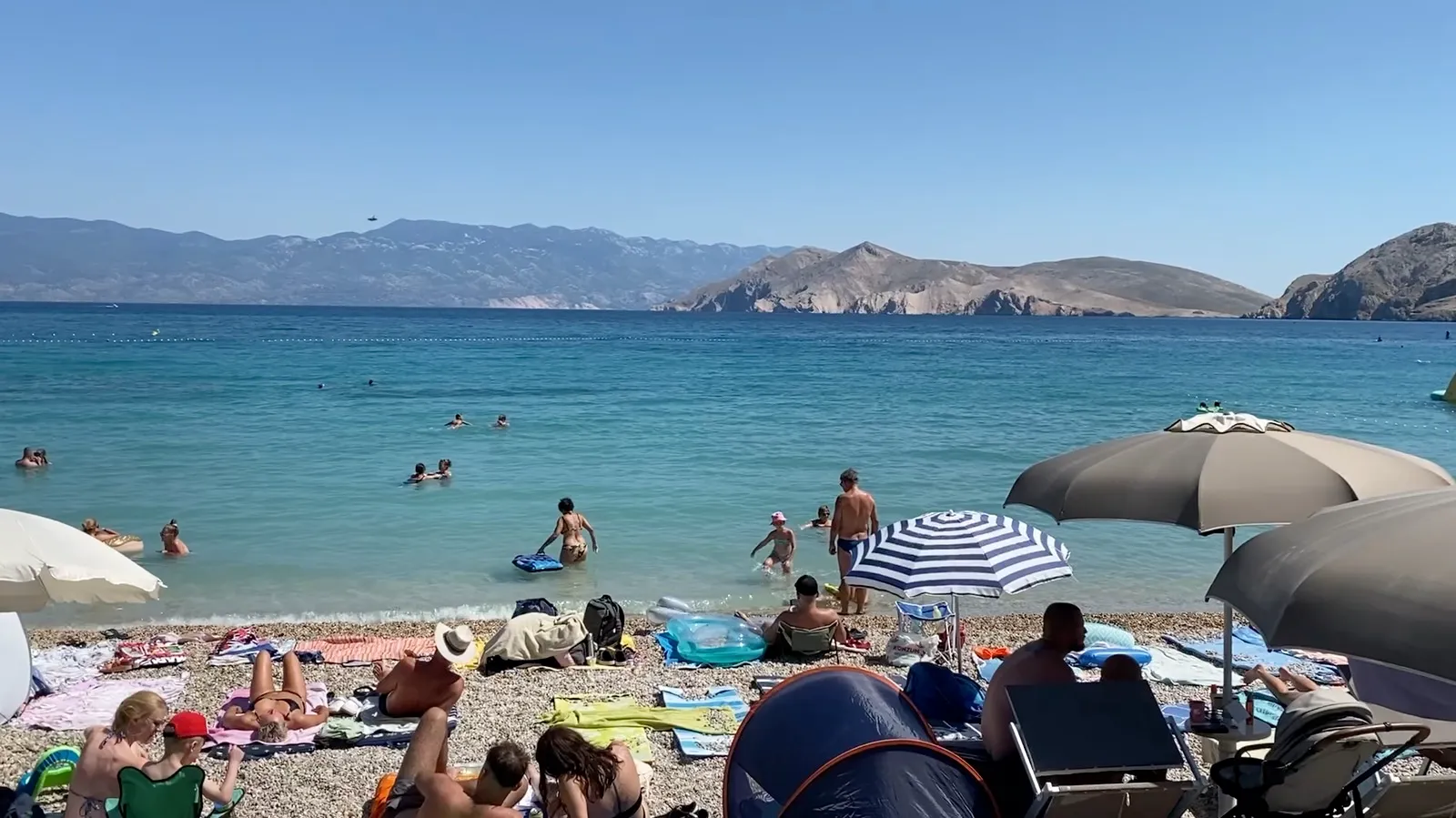 Pebble shoreline and clear water entry at Vela Plaža in Baška