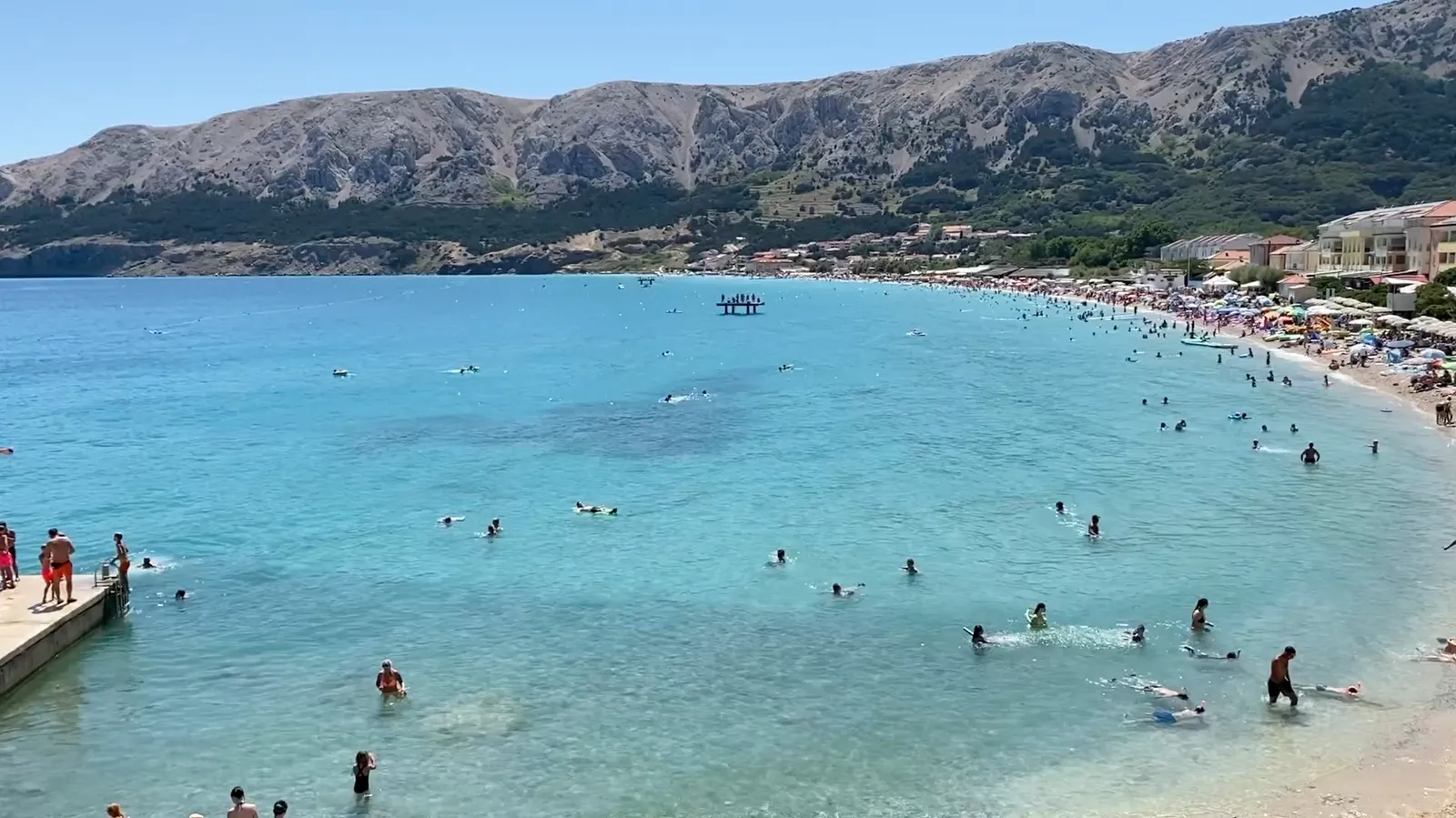 Busy Vela Plaža and clear turquoise water in summer