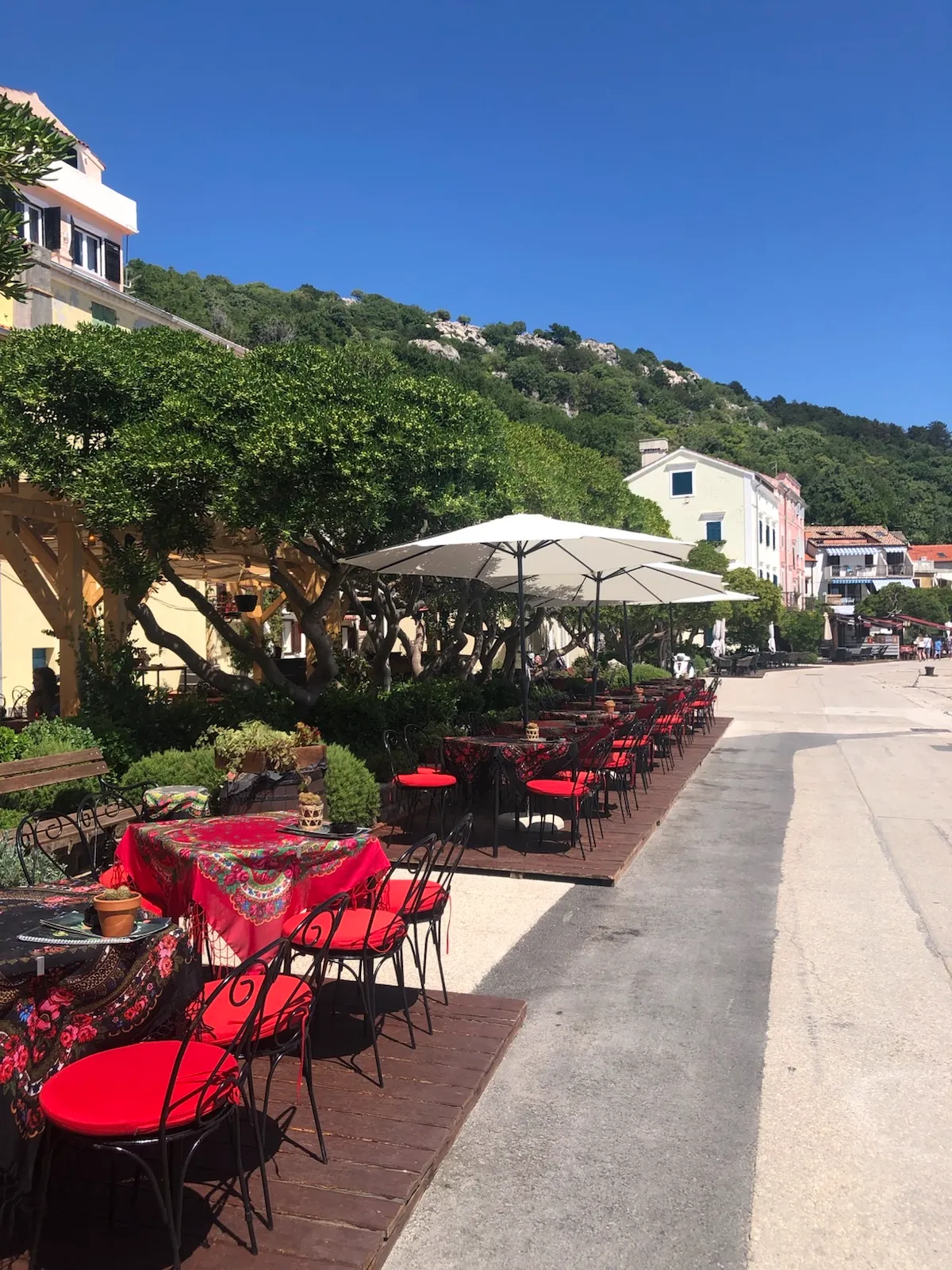 Outdoor café tables along the waterfront promenade in Baška
