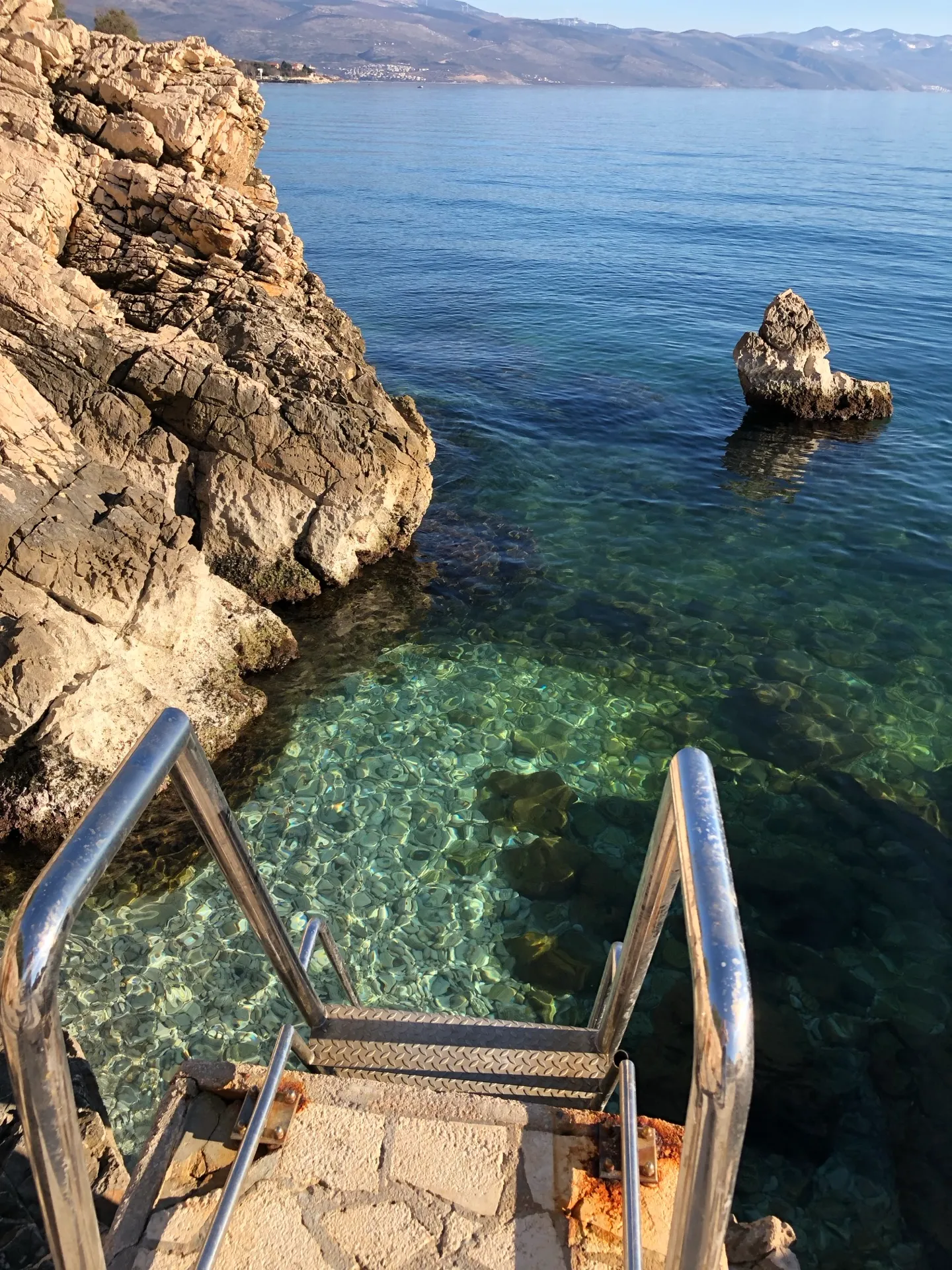 Metal swimming ladder leading into clear Adriatic water