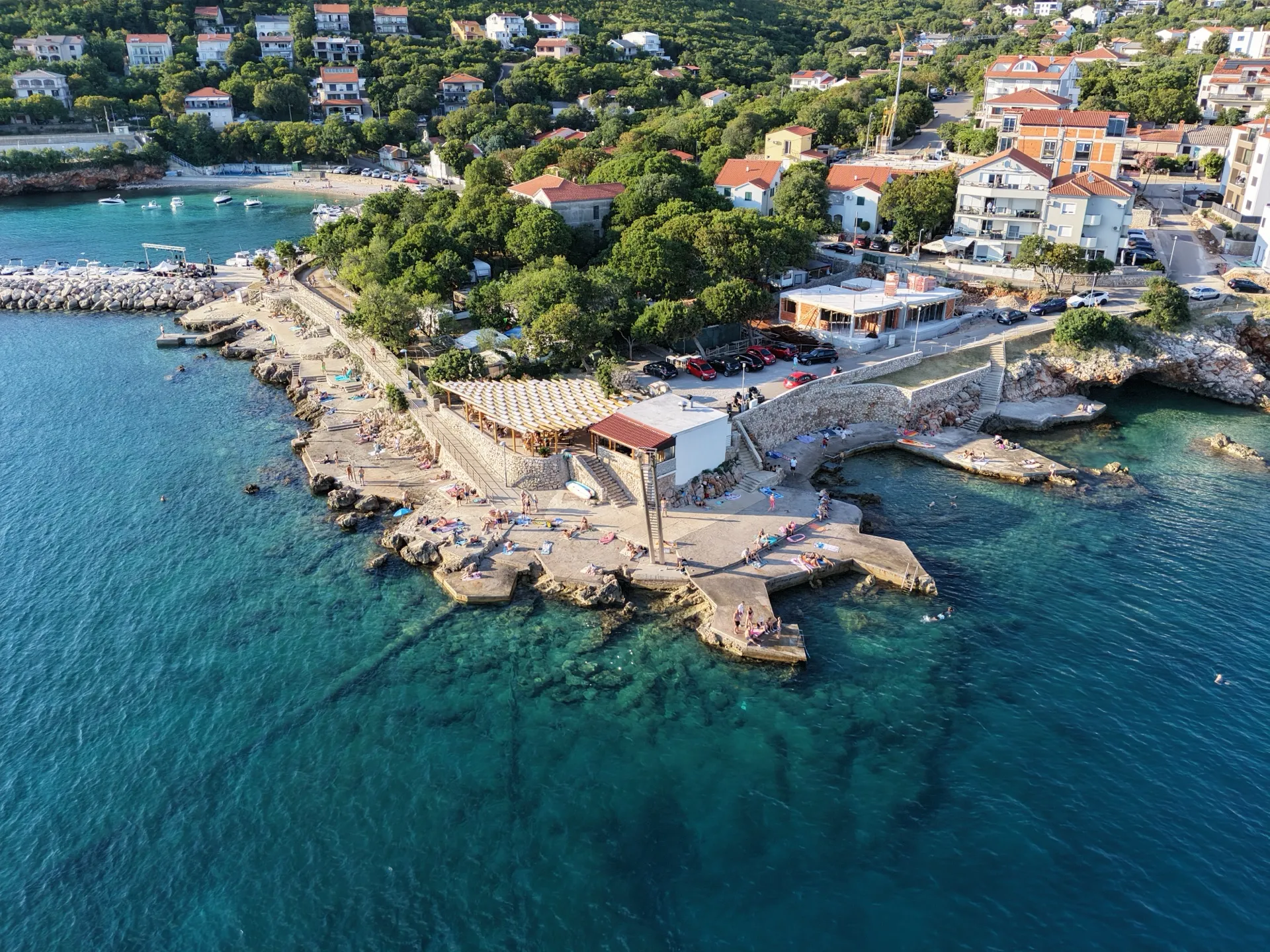 Povile waterfront with rocky swimming spots and coastal buildings